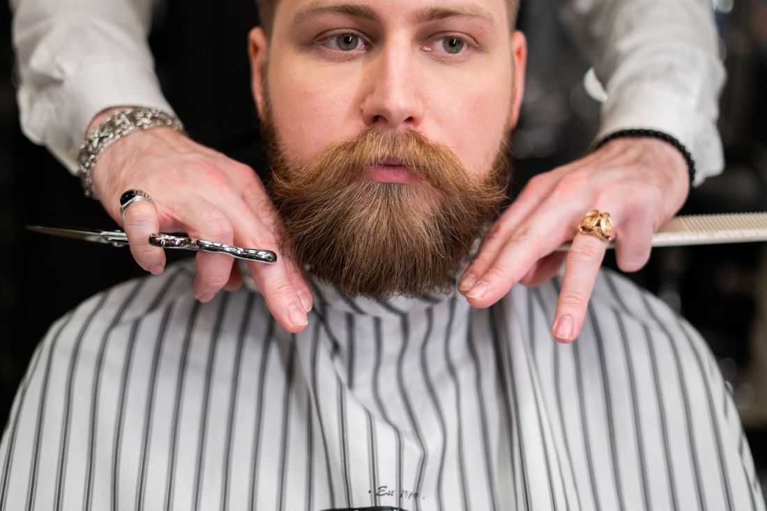 Barber trimming a full beard with scissors