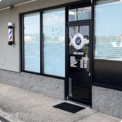 Front door of Mike's Barber Shop with logo and shop hours, barber pole beside it