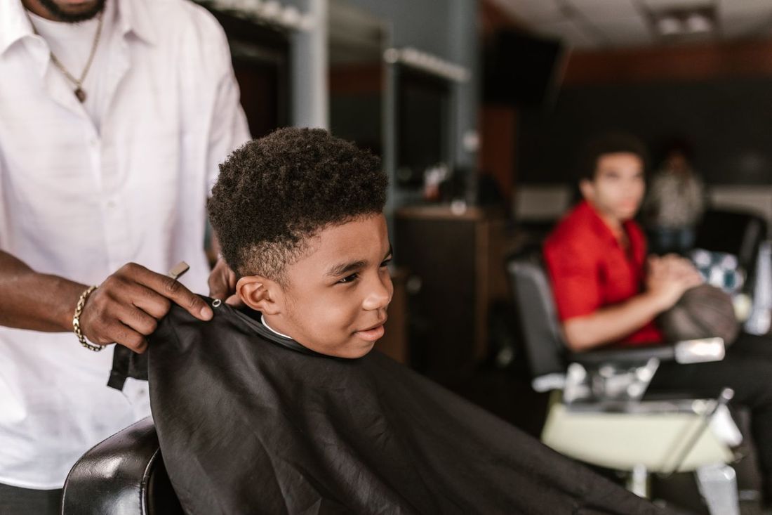 Smiling young boy getting a haircut in a barber chair