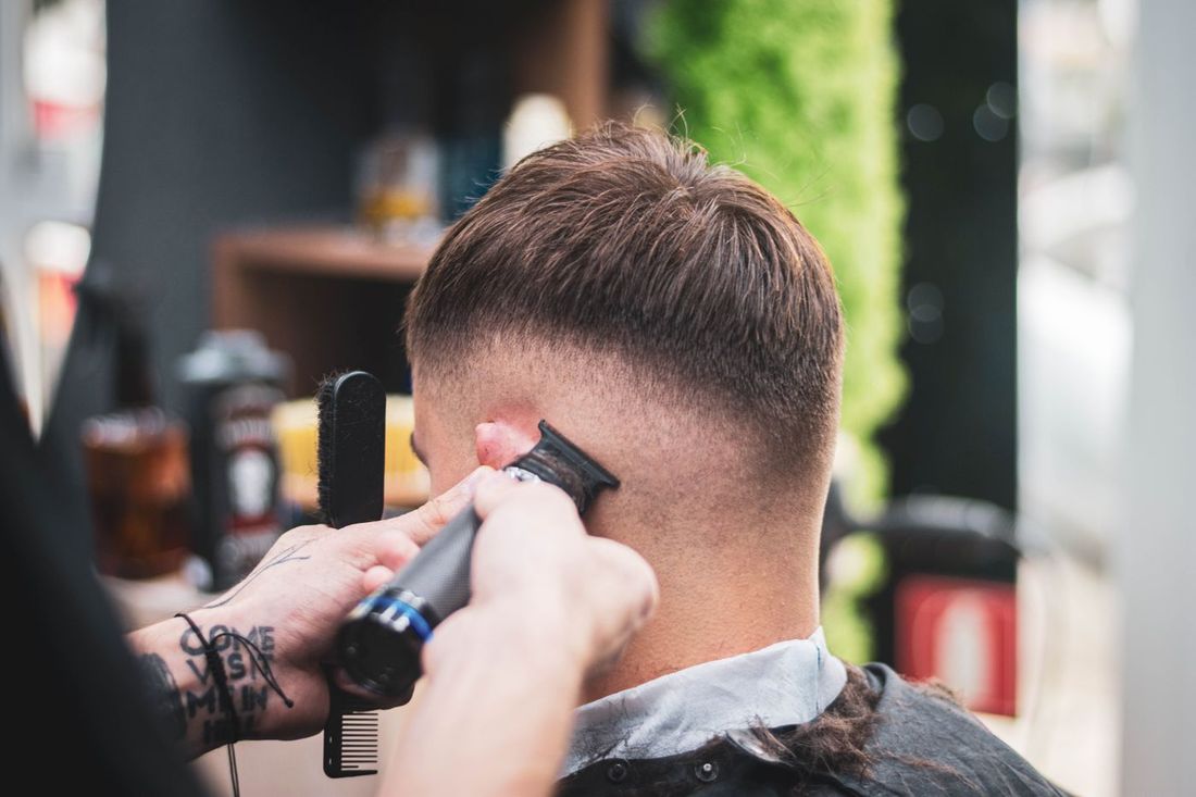 Barber using a trimmer to sharpen a client's hairline