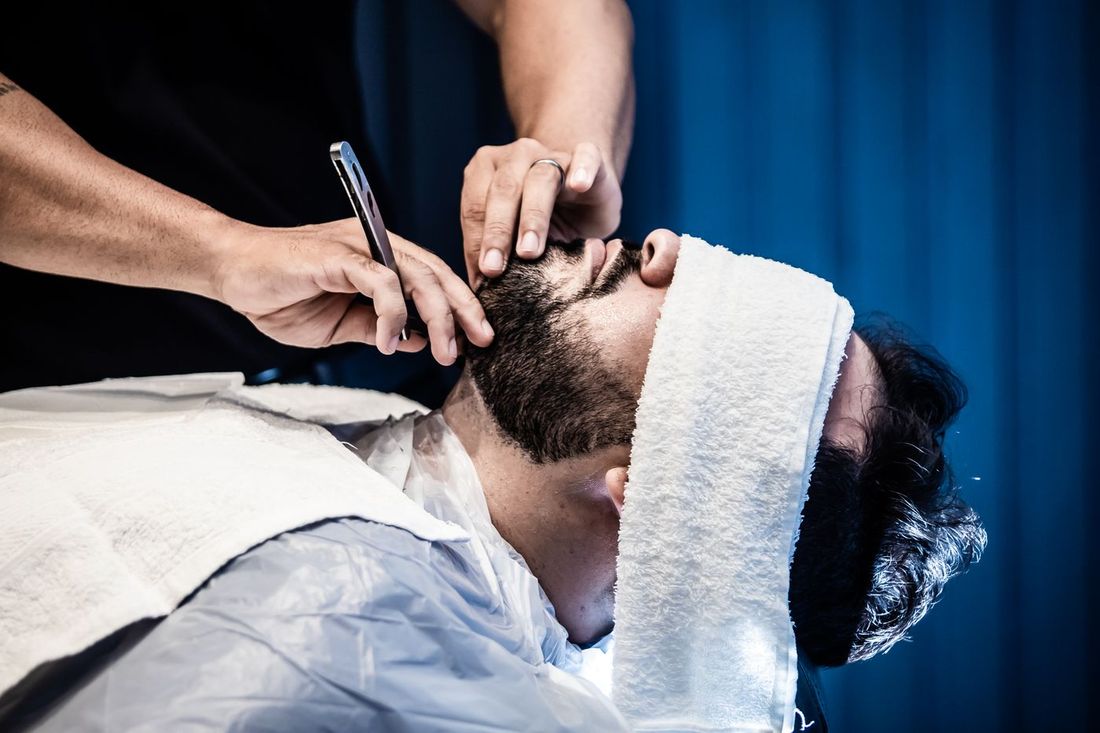 Barber giving a straight-razor shave with a warm towel